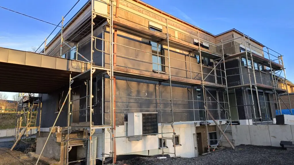 Neubau mit Gerüst: Fenster bereits eingesetzt, Fassadendämmung noch offen