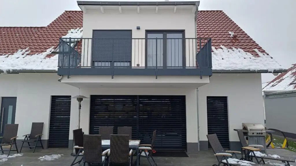 Terrasse mit bodentiefen Schiebeelementen und heruntergelassenem Raffstore