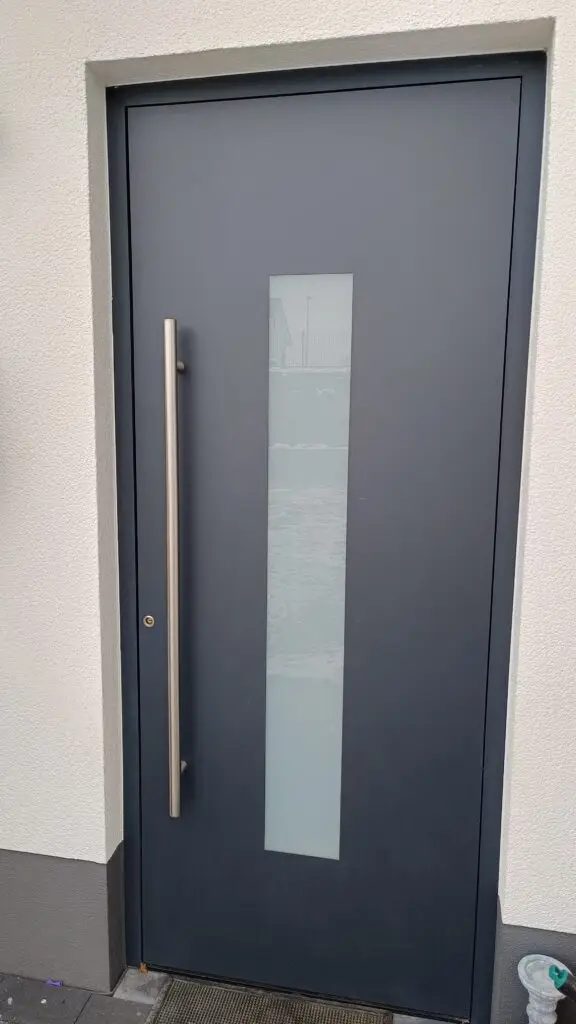 Haustür in Anthrazit mit schmalem Lichtausschnitt und langer Griffstange