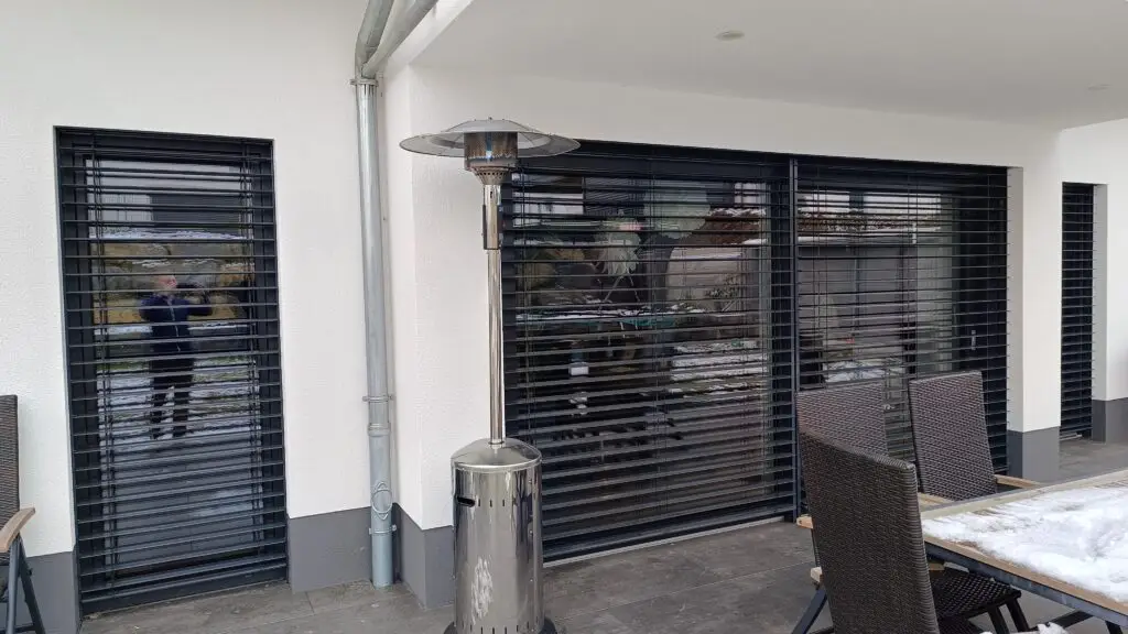 Terrassenseite mit Raffstore an Fenstern und Schiebetür, Lamellen gekippt